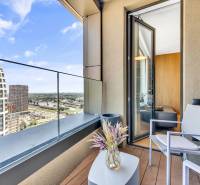 Predaj luxusný 2-izbový byt, 52 m2, Továrenská ul, SKY PARK - Balkón s výhľadom na mesto, konferenčný stolík, stolička a váza s rastlinou.