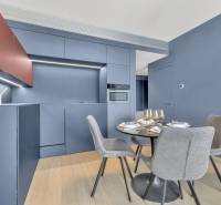 Predaj luxusný 2-izbový byt, 52 m2, Továrenská ul, SKY PARK - Kuchyňa v 2-izbovom byte so štýlovým modrým nábytkom, stolom a podlahou s dreveným dekorom.