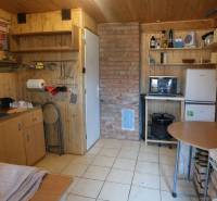 Horská chata na predaj Oščadnica - Kuchynka v chate s dreveným dekorom a tehlovým komínom, vybavená základným nábytkom.