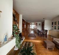 Exk. viacgeneračný RD vo Veľkom Orvišti pri Piešťanoch REZERVOVANÝ - Obývacia izba v rodinnom dome s podlahou s dreveným dekorom, jedálenským stolom a krížom na stene.