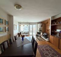 Exk. viacgeneračný RD vo Veľkom Orvišti pri Piešťanoch REZERVOVANÝ - Obývačka v rodinnom dome s podlahou s dreveným dekorom, jedálenským stolom a krbom.