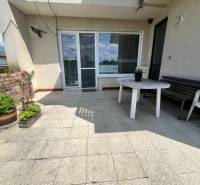 Exk. viacgeneračný RD vo Veľkom Orvišti pri Piešťanoch REZERVOVANÝ - Terasa rodinného domu v Tálovej ulici vo Veľkom Orvišti s plastovým stolom a kvetmi.