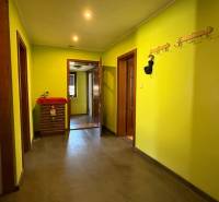 Moderný 5-izbový rodinný dom po kolaudácii 2025 | 2-generačné bývanie  - Chodba s vešiakmi a žltými stenami, podlaha s dreveným dekorom v rodinnom dome.