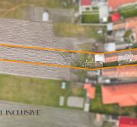 Na predaj 4-izbový rodinný dom, Topoľníky - Rodinný dom v Topoľníkoch so záhradou v orámovaní, viditeľné poľnohospodárske pole a budovy.