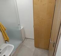 Prenájom garsónka Dubnica nad Váhom  - Kúpeľňa v garsónke s umývadlom, sprchovým kútom a skriňou na svetlej dlažbe.