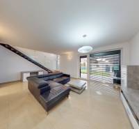 REZERVÁCIA _4-izb.rodinný dom na Okružnej ul.-Senec - Obývacia izba s koženou sedačkou, schodiskom a výhľadom na záhradu z rodinného domu.