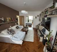 PREDAJ: 3-izbový byt 77 m², Šahy – Výborná investícia aj bývanie  - Obývačka so sedačkou, stolom a podlahou s dreveným dekorom v 3-izbovom byte.