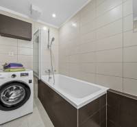 Svetlý 3-izbový byt 90 m² s terasou 18,5 m², 2 garáže, Smaragdová ul. - Kúpeľňa v 3-izbovom byte s vaňou, práčkou a béžovými dlaždicami.