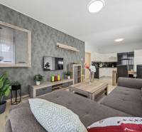 Svetlý 3-izbový byt 90 m² s terasou 18,5 m², 2 garáže, Smaragdová ul. - Obývacia izba v 3-izbovom byte s dreveným dekorom a zariadením, spojená s kuchyňou.