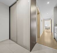 Svetlý 3-izbový byt 90 m² s terasou 18,5 m², 2 garáže, Smaragdová ul. - Chodba v 3-izbovom byte s podlahou s dreveným dekorom a vstavanými skriňami.