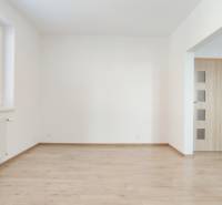 | 2-izbový byt + parking, ul. Východná | Trenčín - Obývacia izba v 2-izbovom byte s podlahou s dreveným dekorom a kuchynským kútom.