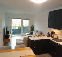 VÝMENA! Nový 2+kk s park. miestom a lodžiou za 3+1, Rača, Bratislava - Interiér 2-izbového bytu s kuchyňou, pohovkou a balkónom, podlaha s dreveným dekorom.