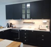 VÝMENA! Nový 2+kk s park. miestom a lodžiou za 3+1, Rača, Bratislava - Kuchyňa v 2-izbovom byte s tmavými skrinkami a dreveným dekorom stola.