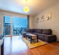 SVETLÝ ZARIADENÝ 2-IZBOVÝ BYT S BALKÓNOM - LA VITA  - Obývacia izba v 2-izbovom byte s podlahou s dreveným dekorom a veľkými oknami.