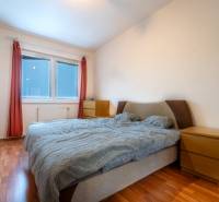 SVETLÝ ZARIADENÝ 2-IZBOVÝ BYT S BALKÓNOM - LA VITA  - Spálňa v 2-izbovom byte s posteľou, prírodnými farbami a podlahou s dreveným dekorom.