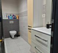 3-izb. byt v obci Blatná na Ostrove, balkón, lodžia, novostavba - Kúpeľňa v 3-izbovom byte so závesným WC, umývadlom, skrinkou a svetlými obkladmi.