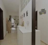 RADO I 4-IZBOVY murovaný ROD.DOM I RAJKA - Chodba v rodinnom dome s bielymi skriňami, dekoráciami a rastlinou.