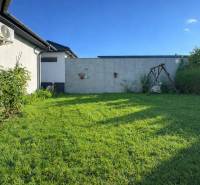 RADO I 4-IZBOVY murovaný ROD.DOM I RAJKA - Záhrada rodinného domu v Rajke s trávnikom, hojdačkou a kríkmi popri stene.