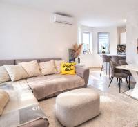 RADO I 4-IZBOVY murovaný ROD.DOM I RAJKA - Obývacia izba v rodinnom dome s pohovkou, jedálenským stolom a podlahou s dreveným dekorom.