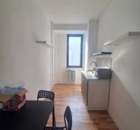 Prenájom priestoru  155 m2, Tulská ul., Zvolen-Západ - Úzka kancelária s čiernym stolom, stoličkami a podlahou s dreveným dekorom.