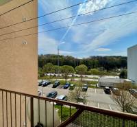 Na prenájom slnečný 2i byt s balkónom, ul. Východná, Trenčín - Výhľad z 2-izbového bytu na ulici Východná zahŕňa parkovisko a zeleň.