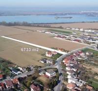 INVESTIČNÝ POZEMOK 6733 m² NA RD – SOKOLOVCE (okres Piešťany) - Pozemky na bývanie v Sokolovciach, okolitá krajina s vodnou plochou v pozadí.