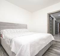 3i byt 73m2 + 6m2 balkón, Gen. Svobodu, Trenčín - Spálňa s posteľou a podlahou s dreveným dekorom v 3-izbovom byte.