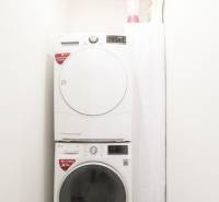 3i byt 73m2 + 6m2 balkón, Gen. Svobodu, Trenčín - Práčka so sušičkou a saponáty v kúpeľni 3-izbového bytu s podlahou s dreveným dekorom.