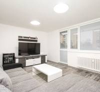 3i byt 73m2 + 6m2 balkón, Gen. Svobodu, Trenčín - Obývačka v 3-izbovom byte so sedačkou, televízorom a podlahou s dreveným dekorom.