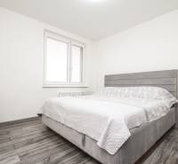 3i byt 73m2 + 6m2 balkón, Gen. Svobodu, Trenčín - Spálňa s posteľou a komodou v 3-izbovom byte, podlaha s dreveným dekorom.