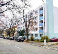 Na predaj moderný 2-izbový byt po kompletnej rekonštrukcii – Piešťany - Ulica Pod Párovcami, Piešťany: Rad áut pri bielej budove, neďaleko 2-izbového bytu.