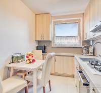 REZERVOVANÉ 4-izbový byt v Trnave na Veternej ulici - Kuchyňa v 4-izbovom byte s jedálenským stolom, krémovými stoličkami a kuchynskou linkou.