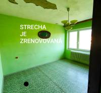 5 izbový dom Mankovce - Izba v rodinnom dome s opadanou omietkou a zelenými stenami.