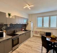 * 7i rodinný dom, veľký 33.5á pozemok, Brestovany - Kuchyňa s podlahou s dreveným dekorom, sivými skrinkami a jedálenským stolom v Rodinnom dome.