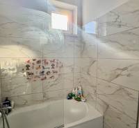 * 7i rodinný dom, veľký 33.5á pozemok, Brestovany - Kúpeľňa v rodinnom dome s vaňou, obklady s mramorovým dekorom a oknom.