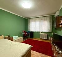 Predaj 3 - izbového bytu - Nová Baňa - Spálňa v 4-izbovom byte s posteľou, červeným kobercom a zelenými stenami.