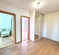 Zrekonštruovaný 3i byt na začiatku Petržalky, električka, les, výhľady - Interiérová fotografia 3-izbového bytu s podlahou v drevenom dekore a vstavanou skriňou.