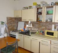 1 - izbový byt Košice, Popradská - Kuchyňa v 1-izbovom byte s kuchynskou linkou, spotrebičmi a dreveným dekorom podlahy.