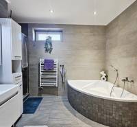 Tehlová novostavba s bazénom a terasou – Geča pri Košiciach - Kúpeľňa v rodinnom dome s rohovou vaňou a svetlým obkladom stien.