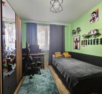 Tehlová novostavba s bazénom a terasou – Geča pri Košiciach - Detská izba s posteľou, stolík, zelené steny a podlaha s dreveným dekorom v rodinnom dome.