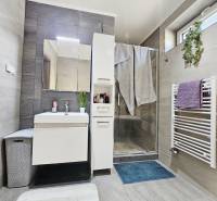 Tehlová novostavba s bazénom a terasou – Geča pri Košiciach - Kúpeľňa s umývadlom, sprchovým kútom, bielym nábytkom a radiátorom v rodinnom dome.