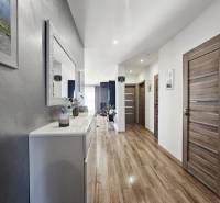 Tehlová novostavba s bazénom a terasou – Geča pri Košiciach - Chodba v rodinnom dome s podlahou s dreveným dekorom, skriňami a zrkadlom na stene.