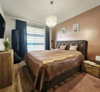 Tehlová novostavba s bazénom a terasou – Geča pri Košiciach - Spálňa v rodinnom dome s posteľou, televízorom a podlahou s dreveným dekorom.