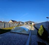 Tehlová novostavba s bazénom a terasou – Geča pri Košiciach - Dvor rodinného domu v Geči s bazénom a kameňmi pokrytým chodníkom.