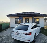 Tehlová novostavba s bazénom a terasou – Geča pri Košiciach - Rodinný dom v Geči s dláždeným dvorom a zaparkovaným bielym automobilom.