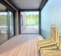 LUXUSNÝ 3i byt,PARKING,CHLADENIE,TERASA,Grand Koliba, Frankovská ulica - Terasa v 3-izbovom byte so sklenenými stenami a pohodlnými drevenými kreslami.