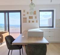 LUXUSNÝ 3i byt,PARKING,CHLADENIE,TERASA,Grand Koliba, Frankovská ulica - Svetlá obývacia izba s kuchyňou v 3-izbovom byte s veľkými oknami a hnedou sedačkou.