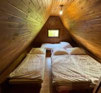 NA PREDAJ Chata na Duchonke- Prašice - Podkrovná izba na chate s drevenými stenami a dvoma posteľami.