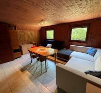 NA PREDAJ Chata na Duchonke- Prašice - Interiér chaty so sedačkou, jedálenským stolom a drevenými stenami.