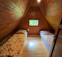 NA PREDAJ Chata na Duchonke- Prašice - Drevený interiér chaty s dvoma postelemi a podlahou s dreveným dekorom.